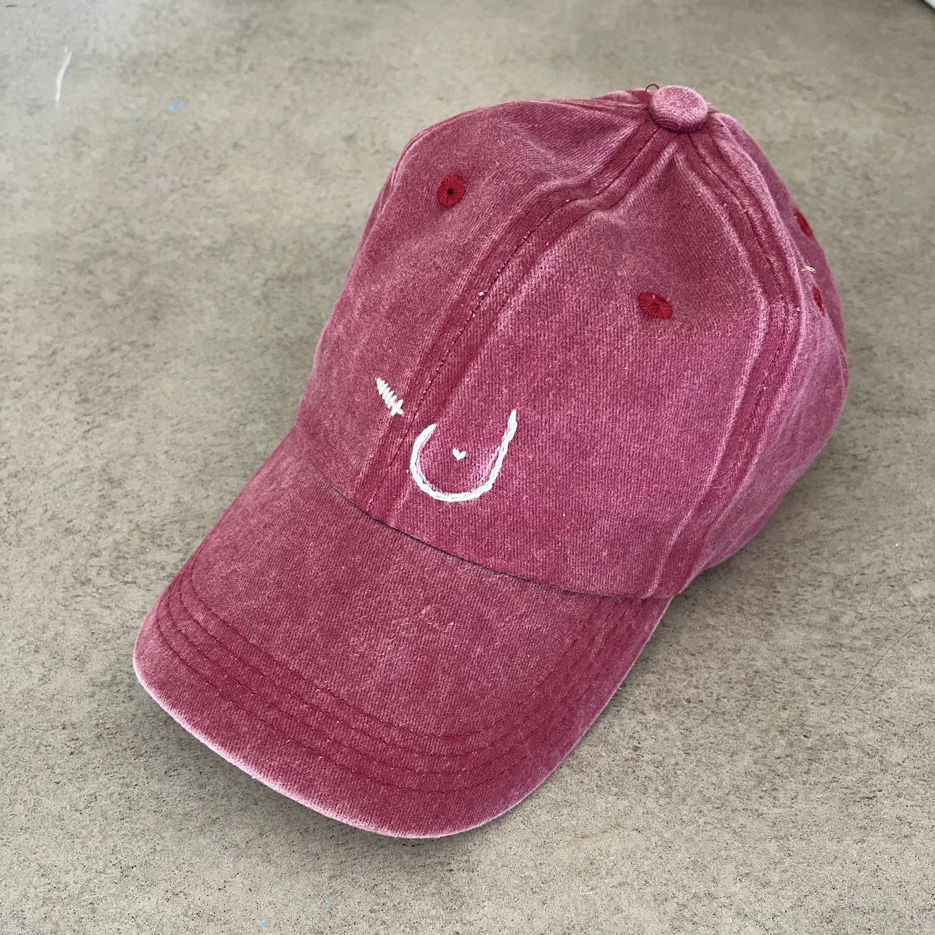 Maroon cap with a white custom design on a gray surface