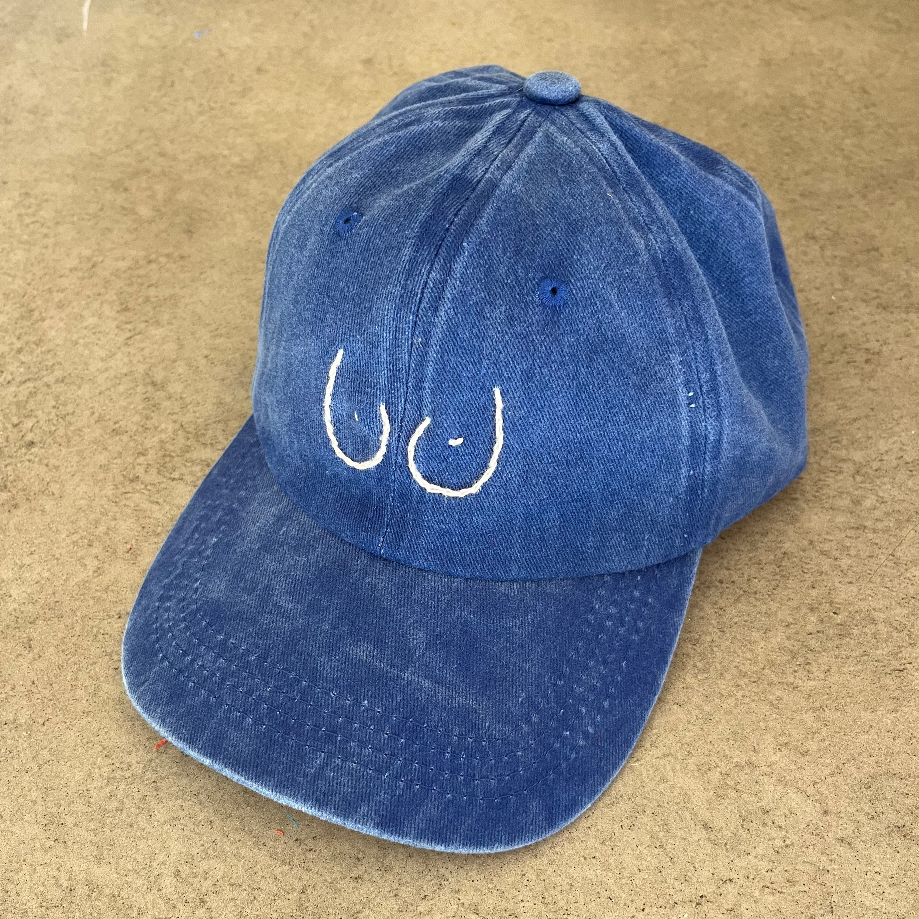 Blue cap with white embroidered design on a beige surface