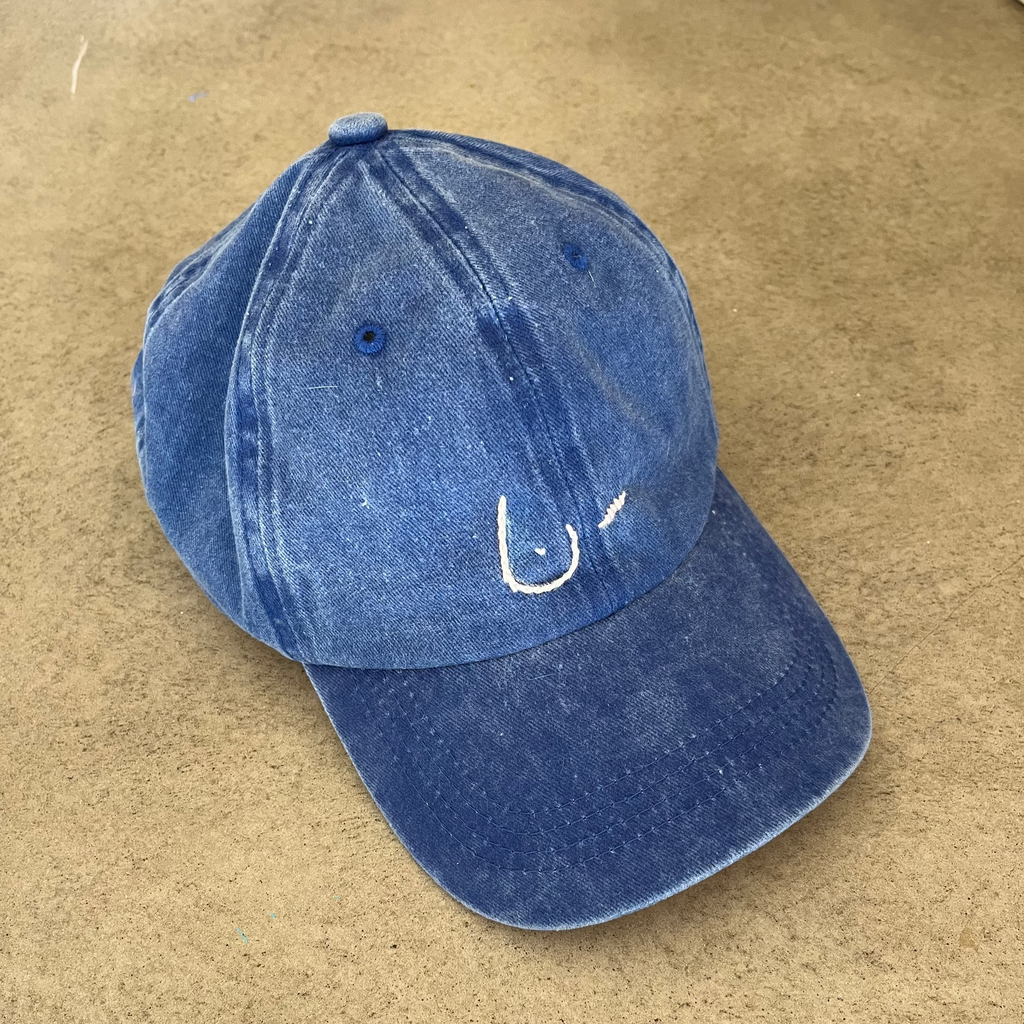 Blue denim cap with a white logo on a beige surface