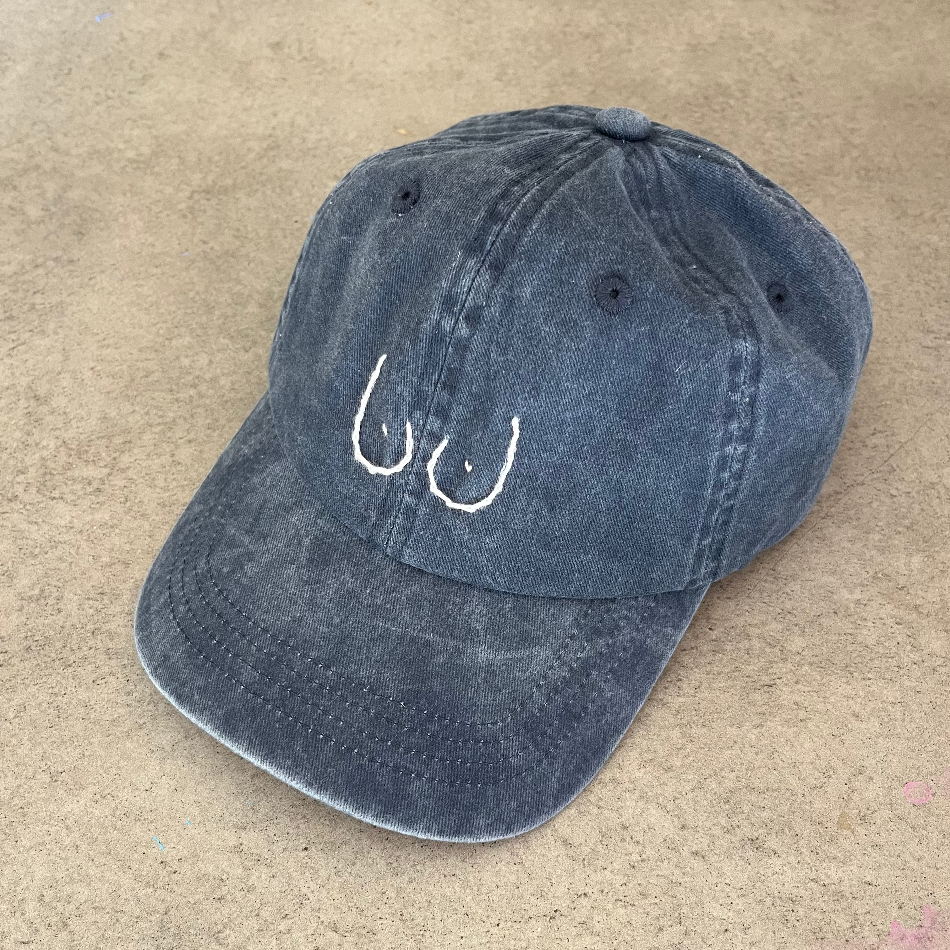 Blue cap with breast design on a beige surface