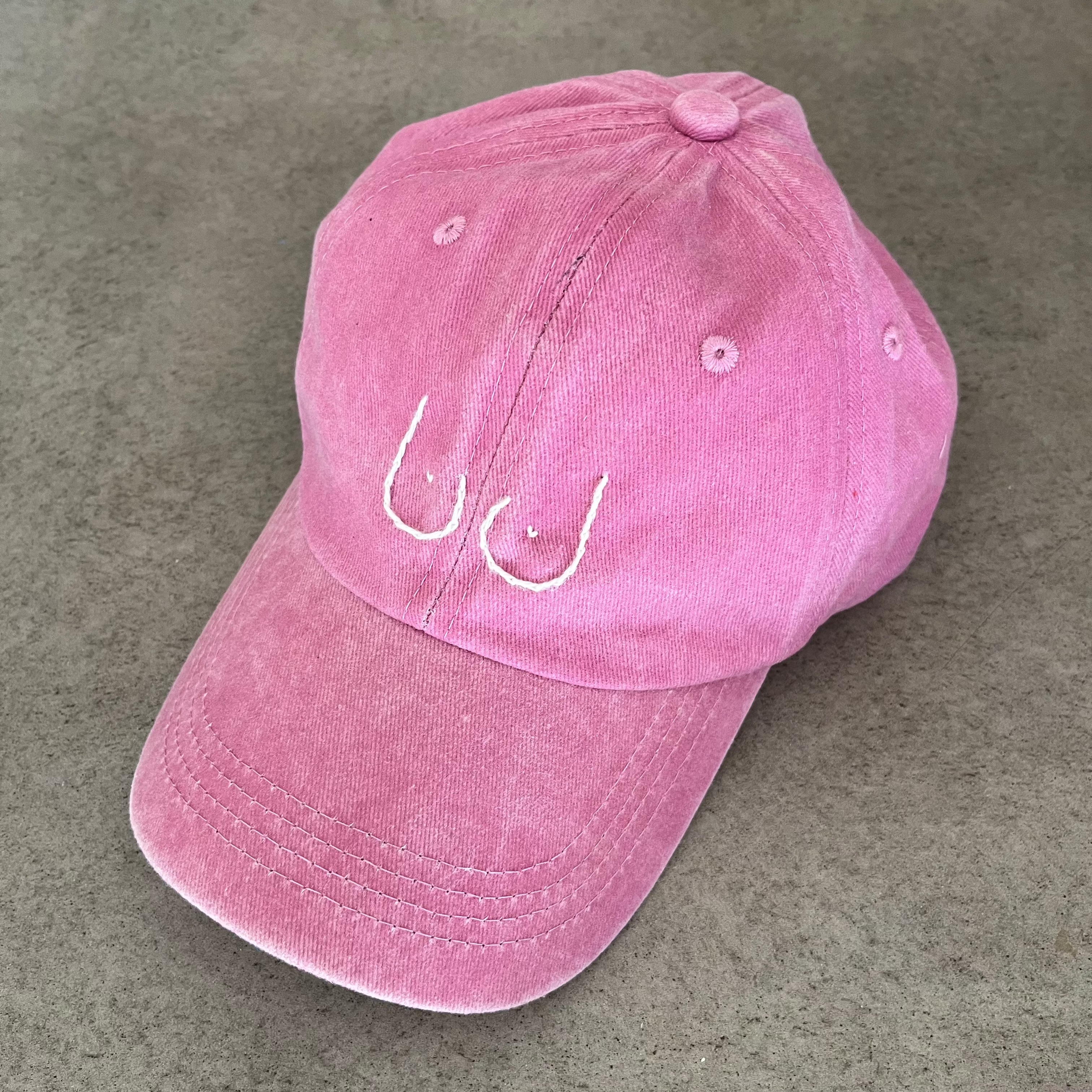 Pink cap with a logo on a gray concrete surface
