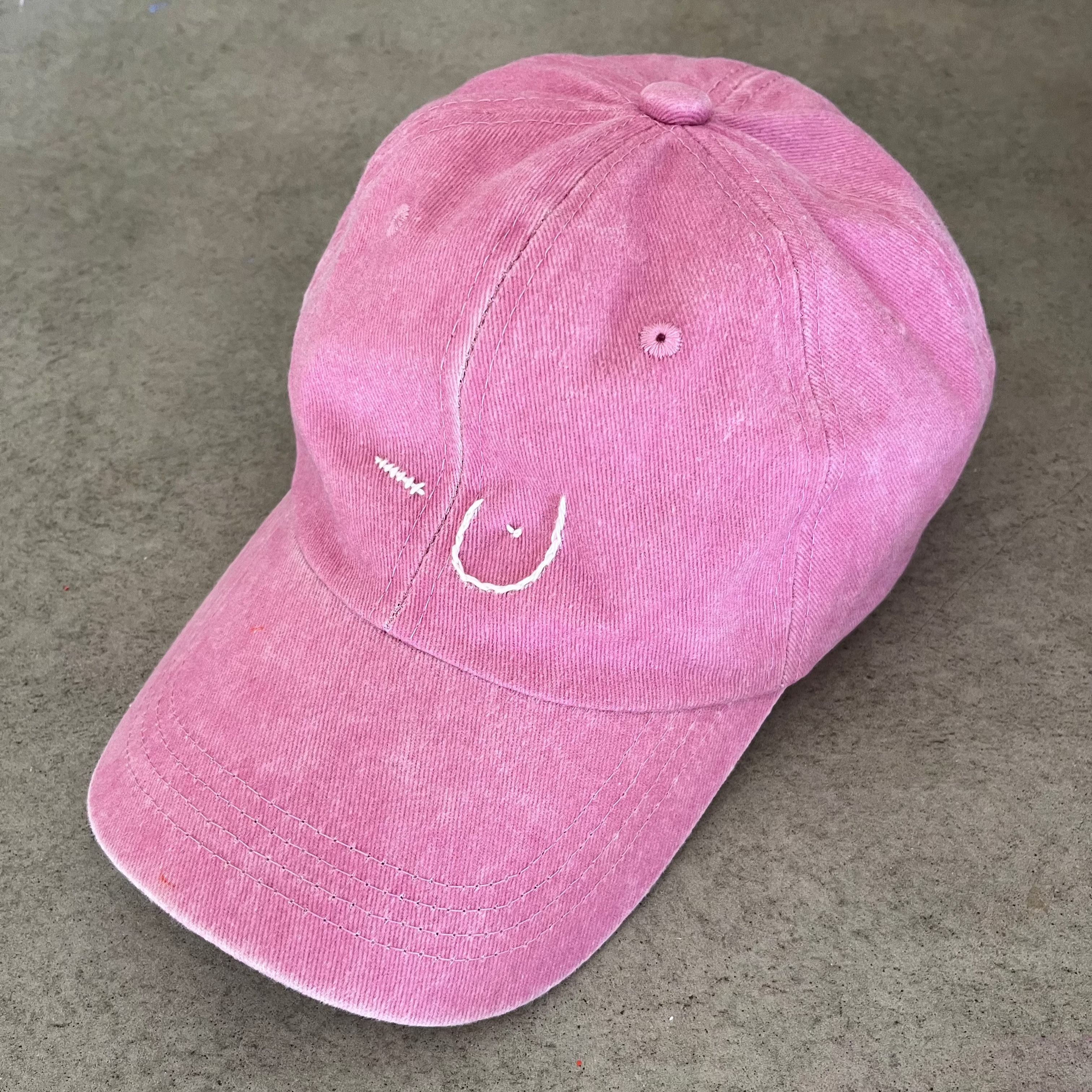 Pink baseball cap on a concrete surface